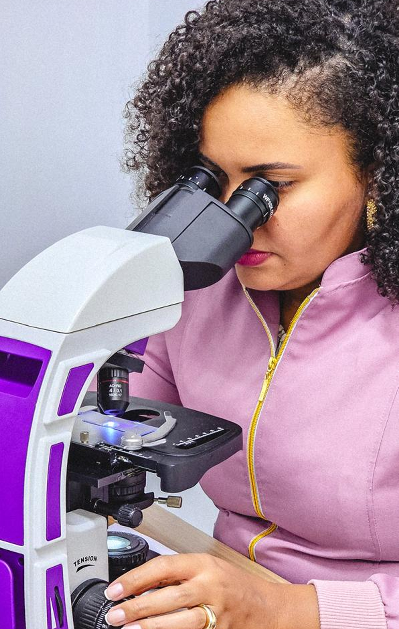Dra. Rayule Cristina analisando uma amostra ao microscópio na Dermatopet